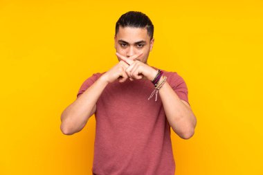 Asyalı yakışıklı adam sarı arka planda izole edilmiş İtalyan jestleri yapıyor.