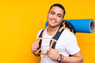 Tecrit edilmiş arka planda büyük bir sırt çantası olan genç dağcı.