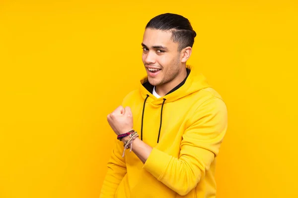 Asian handsome man isolated on yellow background laughing in lateral position