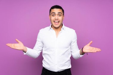 Asyalı yakışıklı adam mavi arka planda izole edilmiş ve şok olmuş bir yüz ifadesi var.