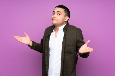 Asyalı yakışıklı adam mavi arka planda izole edilmiş şüpheli hareketler yapıyor.