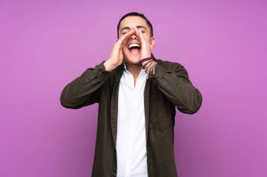 Asyalı yakışıklı adam mavi arka planda izole edilmiş bağırıyor ve bir şey duyuruyor.