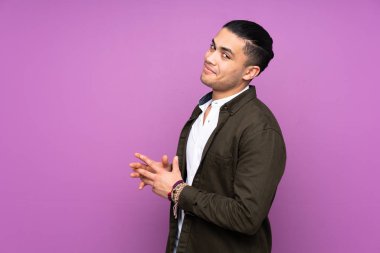 Asyalı yakışıklı adam mavi arka planda bir şeyler çeviriyor.