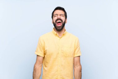Mavi arka planda sakallı genç bir adam ağzı açık bağırıyor.