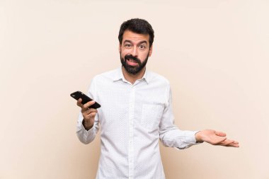 Sakallı genç adam bir şey anlamadığı için mutsuz bir cep telefonu tutuyor.
