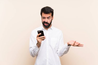 Elinde cep telefonu olan sakallı genç bir adam şüpheli hareketler yapıyor.