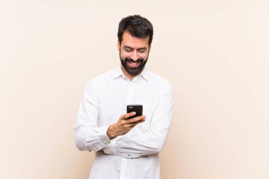 Cep telefonu tutan sakallı genç adam cep telefonuyla mesaj yolluyor.