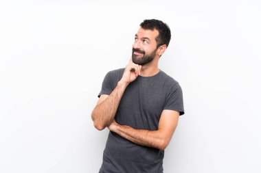 Soyutlanmış beyaz arka planda genç yakışıklı bir adam yukarı bakarken bir fikir düşünüyor.