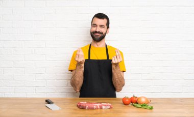 Aşçı mutfakta para jesti yapıyor.