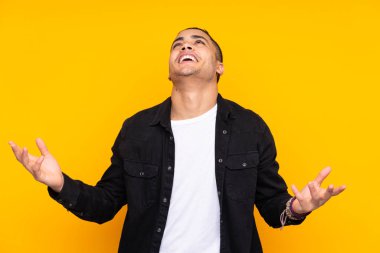 Asyalı yakışıklı adam sarı arka planda yalnız gülüyor.