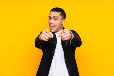 Asyalı yakışıklı adam sarı arka planda izole edilmiş güçlü bir jest yapıyor.