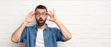 Beyaz tuğlalı duvarın üzerinde sakallı yakışıklı bir adam.