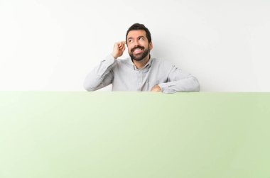 Sakallı genç yakışıklı adam elinde kocaman boş bir pankartla bir fikir düşünüyor.