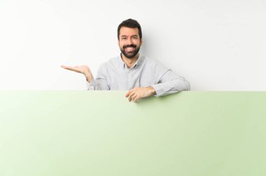 Sakallı genç yakışıklı bir adam elinde kocaman boş bir levha tutuyordu. Avucunda hayali bir şey vardı. Bir ilan vermek için.
