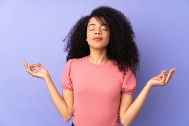 Genç Afrikalı Amerikalı kadın, mor arka planda zen pozuyla izole edilmiş.