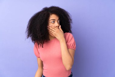 Mor arka planda izole edilmiş genç Afrikalı Amerikalı kadın yan tarafa bakarken sürpriz jest yapıyor.