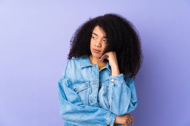 Genç Afrikalı Amerikalı kadın, mor arka planda yalnız başına, yorgun ve sıkılmış bir ifadeyle.