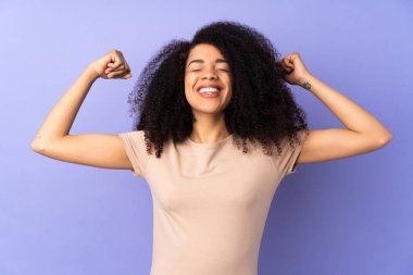 Genç Afrikalı Amerikalı kadın, mor arka planda izole edilmiş, güçlü bir jest yapıyor.