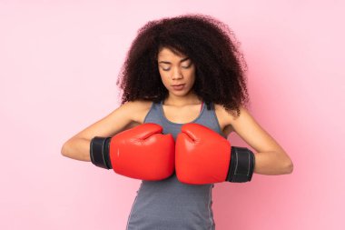 Genç Afrikalı Amerikalı spor kadın pembe arka planda boks eldivenleriyle izole edilmiş.