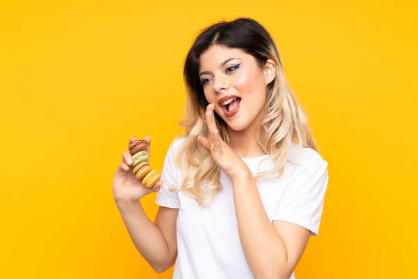 Tiener Meisje Geïsoleerd Gele Achtergrond Met Kleurrijke Franse Macarons Fluisteren — Stockfoto