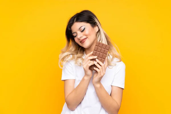 Teenager Dívka Izolované Žlutém Pozadí Čokoládovou Tabletu Šťastný — Stock fotografie