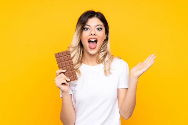Teenager Dívka Izolované Žlutém Pozadí Čokoládovou Tabletu Překvapený — Stock fotografie
