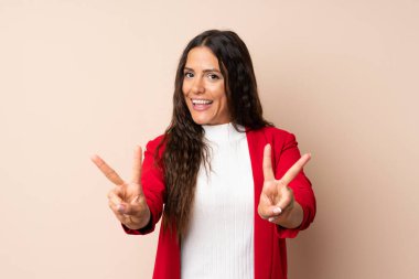 Arka planda kalmış genç bir kadın gülümsüyor ve zafer işareti gösteriyor.