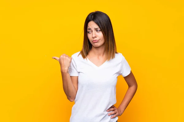 Giovane Donna Sfondo Giallo Isolato Infelice Indicando Lato — Foto Stock