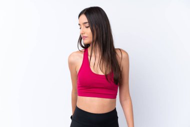 İzole edilmiş beyaz arka planda esmer, genç bir kadın bacak esnetiyor.