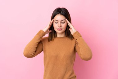 Soyutlanmış pembe arka planda baş ağrısı olan genç bir kadın.