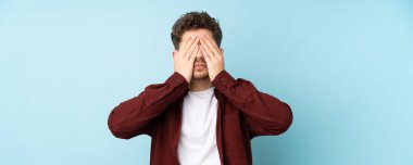 Kafkasyalı genç adam arka planı izole ederek gözleri elleriyle kapatıyor.