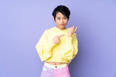 Mor arka planda kısa saçlı genç Vietnamlı kadın geç kalma jesti yapıyor.