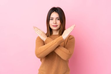 Soyutlanmış pembe arka planı olan genç bir kadın jest yapmıyor.