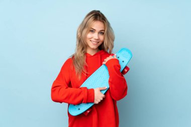 Genç Rus kız mutlu bir ifadeyle mavi arka planda izole edilmiş.