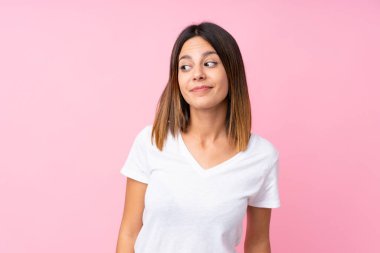 Soyutlanmış pembe arka planda genç bir kadın şüpheli hareketler yapıyor.