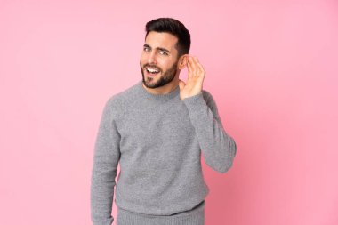 Kafkasyalı yakışıklı adam izole edilmiş arka planda bir şeyler dinlerken elini kulağına koydu.