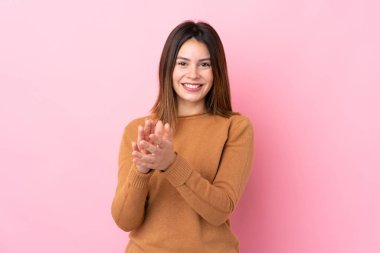 Soyutlanmış pembe arka planda genç bir kadın bir konferanstan sonra alkışlıyor.