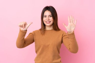 Soyutlanmış pembe arka planda altı parmaklı genç kadın.