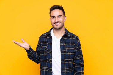 Avuç üzerinde copyspace hayali tutan izole sarı arka plan üzerinde Genç yakışıklı adam