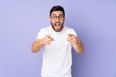 Kafkasyalı yakışıklı, soyutlanmış arka planda şaşırmış ve ön tarafı işaret ediyor.