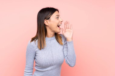 Soyutlanmış pembe arka planda, ağzı sonuna kadar açık bağıran bir kadın.