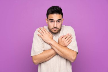 Soyutlanmış mor arka planda genç yakışıklı adam donuyor.
