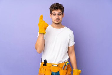 Mor arka planda izole edilmiş genç elektrikçi işaret parmağıyla işaret etmek harika bir fikir.