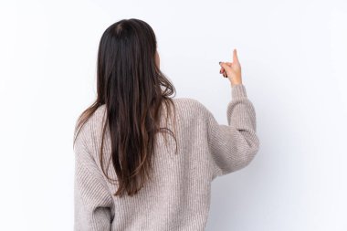 İzole edilmiş beyaz arka planda genç esmer kadın işaret parmağıyla işaret ediyor.