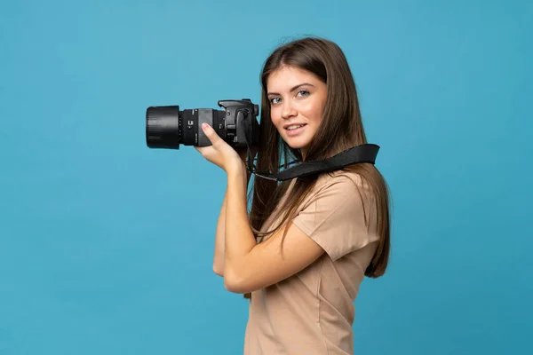 Jonge Vrouw Geïsoleerde Blauwe Achtergrond Met Een Professionele Camera — Stockfoto