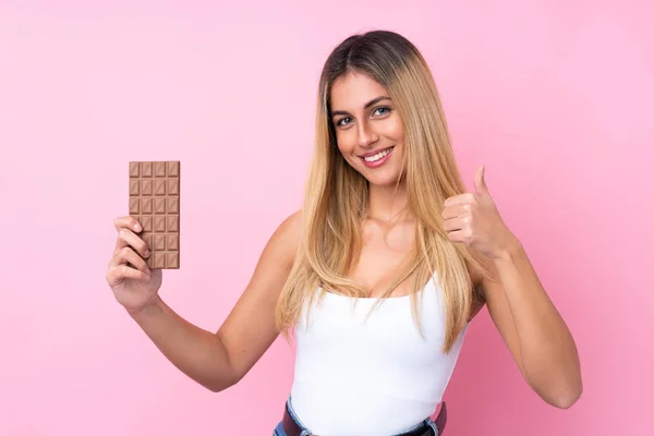 Mladá Uruguayská Žena Přes Izolované Růžové Pozadí Čokoládovou Tabletu Palcem — Stock fotografie