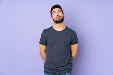 Kafkasyalı yakışıklı bir adam ve izole edilmiş mor arka plana bakıyor.