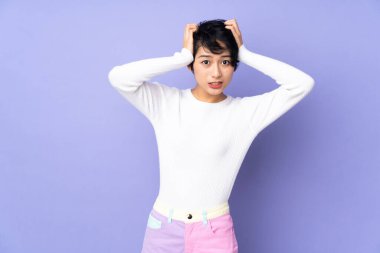 Mor arka planda kısa saçlı Vietnamlı genç bir kadın gergin hareketler yapıyor.