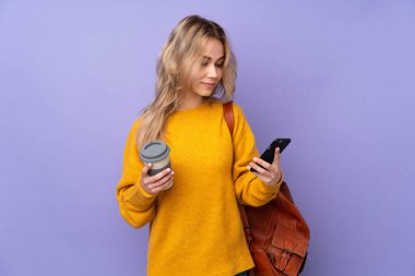 Mor arka planda izole edilmiş genç bir Rus öğrenci. Elinde kahve ve cep telefonu var.