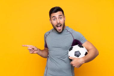 İzole edilmiş arka plandaki futbolcu şaşırdı ve parmağını yana çevirdi.